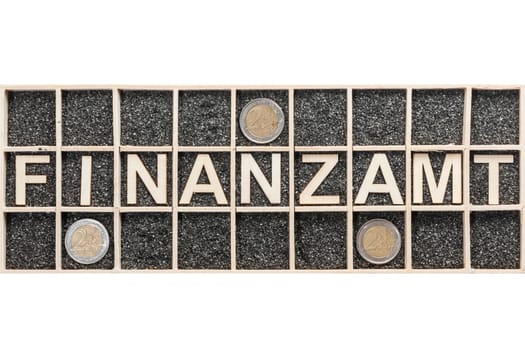 Plywood letters arranged in a collecting box with black decorative sand representing the word FINANCE and three euro coins in adjacent compartments on white background.