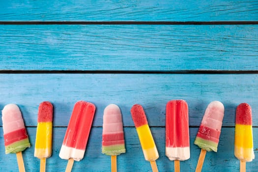 Colorful fruit ice cream stick look fresh to eat placed on a blue vintage wooden. Focus on ice crean sticks.