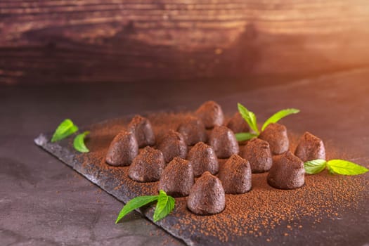 Homemade chocolate truffles with mint sprinkled with cocoa powder on slate. Focus on truffles