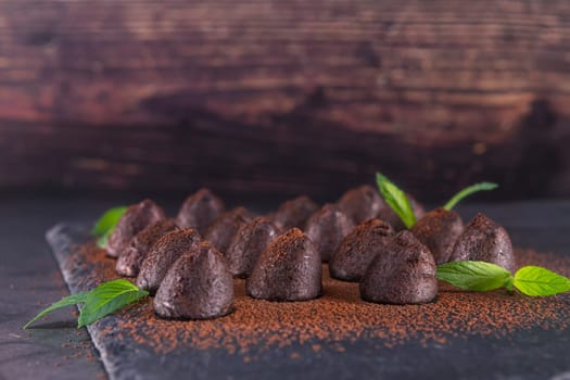 Homemade chocolate truffles with mint sprinkled with cocoa powder on slate. Focus on truffle