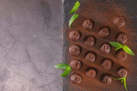 Top view of delicious chocolate truffles powdered with cocoa on slate.