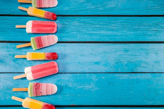 Colorful fruit ice cream stick look fresh to eat placed on a blue vintage wooden. Focus on ice crean sticks.