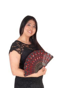 A beautiful Asian woman standing in profile in a black dress holding.her nice fan in her hand, isolated for white background.