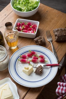 plate with radish, butter and salad on a table