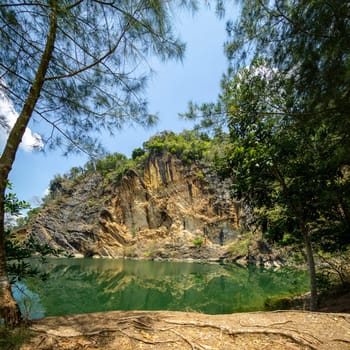 Emerald green pond.Caused by digging limestone mines Blue sky and white clouds , Tons of wood covered