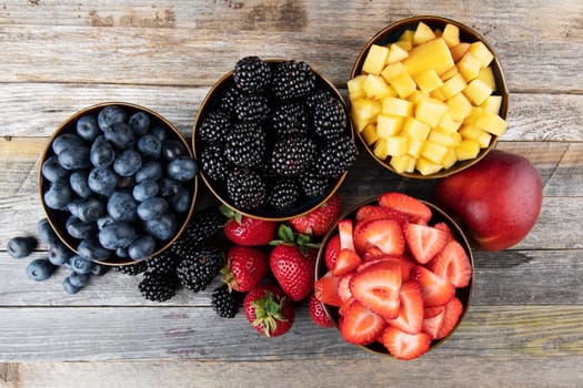 Flat lay of fres strawberries, blueberries, blackberreis and nectaries in bowls.