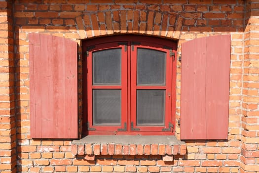 Classic wooden window with shutters on red brick wall