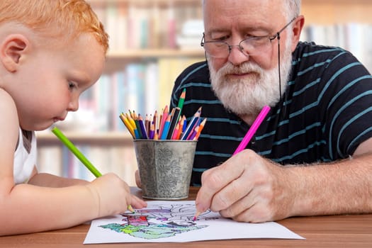 Grandpa working together and coloring on a drawing with his little grandson