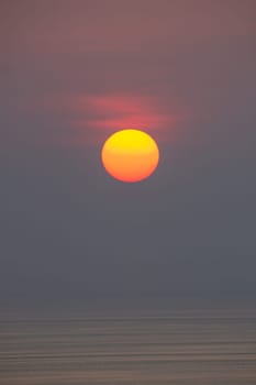 The sun is falling into the sea. , The sky is orange And the sea is dark