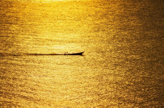 The sunset, the sea surface reflects the sunlight in gold. The ship ran through the sparkling sea surface.