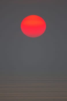 The sun is falling into the sea. It is colour orang The sky and the sea is dark