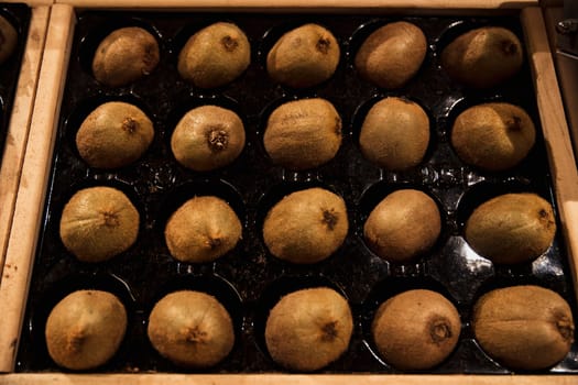 A close-up shot of an abundance of fresh Kiwi on display at a market stall.