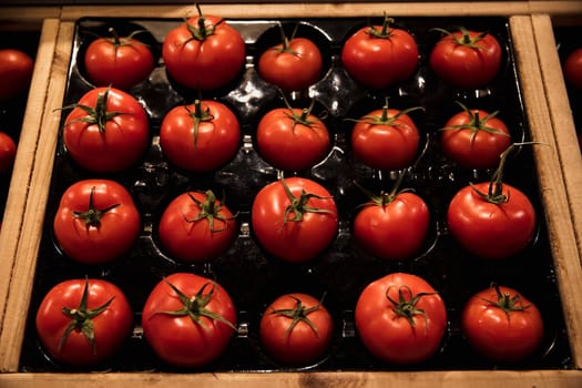 A close-up shot of an abundance of fresh Red Tomatoes on display at a market stall.