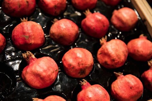 A close-up shot of an abundance of fresh Pomegranate on display at a market stall.