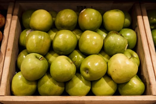 A close-up shot of an abundance of fresh Green Apples on display at a market stall.