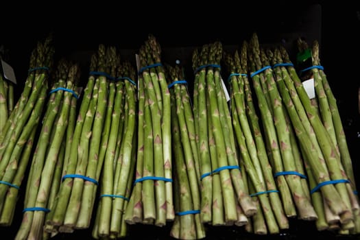 A close-up shot of an abundance of fresh aspparagus on display at a market stall.