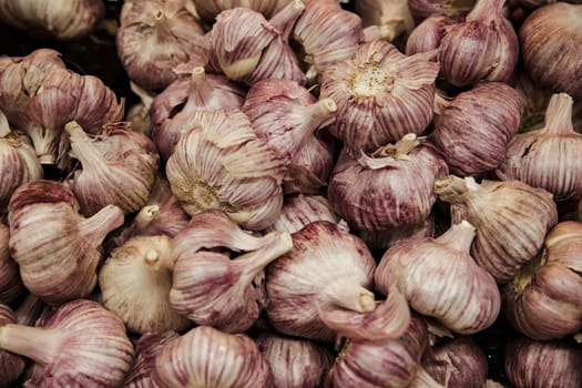 A close-up shot of an abundance of fresh garlic bulbs on display at a market stall.
