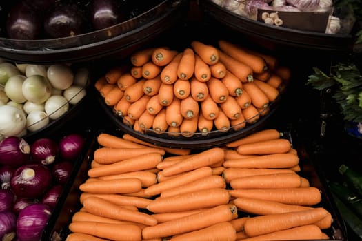 A close-up shot of an abundance of fresh vegetables on display at a market stall.