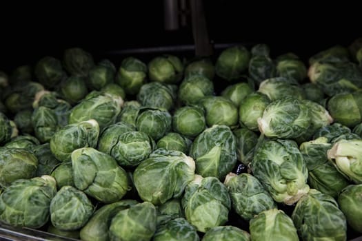 A close-up shot of an abundance of fresh Brussels Sprouts on display at a market stall.
