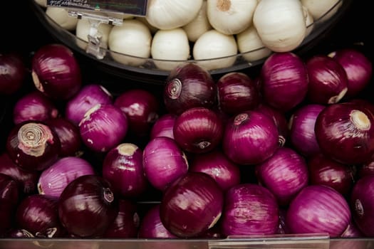 A close-up shot of an abundance of fresh onions on display at a market stall.