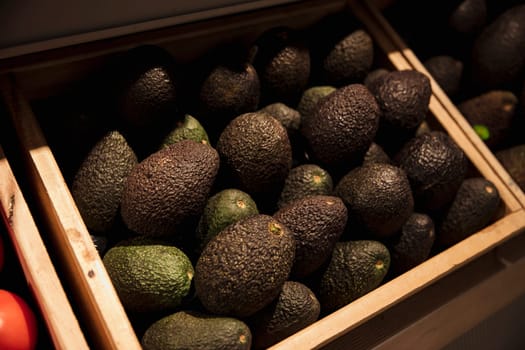 A close-up shot of an abundance of fresh Avocado's on display at a market stall.