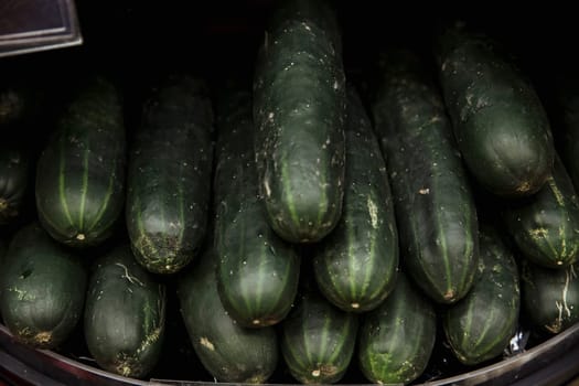 A close-up shot of an abundance of fresh courgette's on display at a market stall.