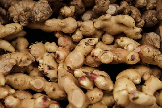 A close-up shot of an abundance of fresh ginger on display at a market stall.