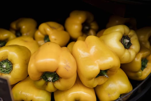 A close-up shot of an abundance of fresh Yellow peppers on display at a market stall.