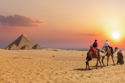 The Pyramid complex of Giza and arabs on camels, Egypt.