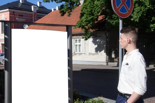Man looking at empty billboard standing in outdoors on street