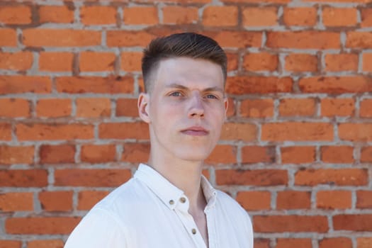 Portrait of a casually dressed young businessman standing against a brick wall