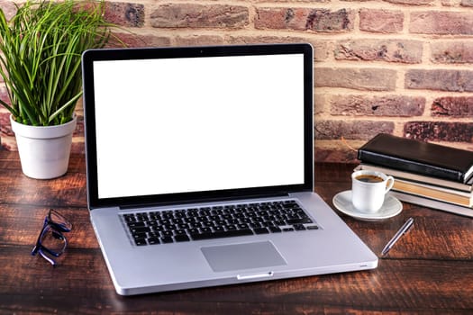 Laptop notebook with blank screen and cup of coffee and notepad pen and books and smart-phone on wooden table. Mock up on wooden table with laptop with blank screen, cup of coffee, pen, books and flower. Focus on keyboard.