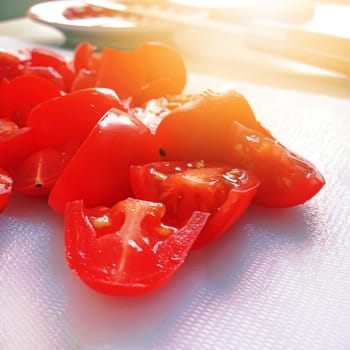 close-up view of sliced ​​cherry tomatoes on a white cutting board. Cooking and healthy food concept