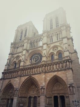 Notre Dame de Paris cathedral facade in a foggy morning. Gorgeous gothic architecture.