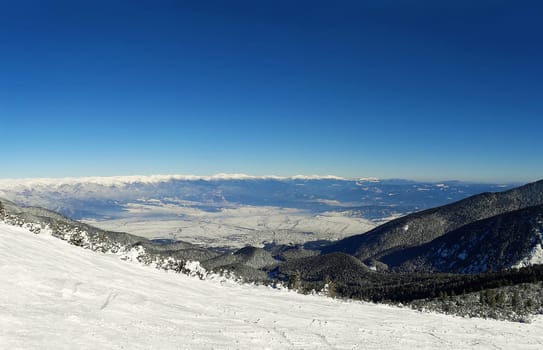 Ski slope and panorama of winter mountains. Alpine ski resort Bansko, Bulgaria