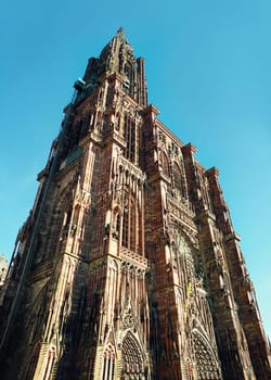 The tower of Roman Catholic Cathedral Notre Dame of Strasbourg in Alsace, France. Beautiful sunny day with clear blue sky. Majestic gothic architecture.