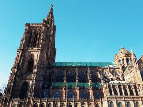 Side view of Roman Catholic Cathedral Notre Dame de Strasbourg in Alsace, France. Beautiful sunny day with clear blue sky. Majestic gothic architecture.