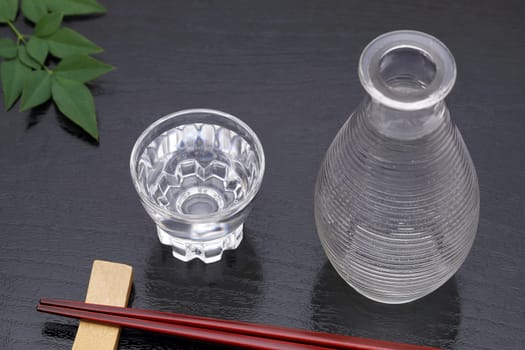 Japanese sake in transparent glass cup and jar on black background