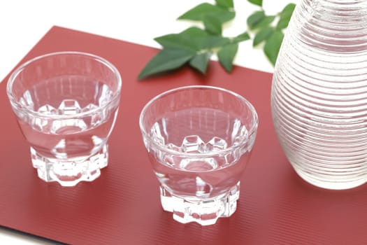 Japanese sake in transparent glass cup and jar on white background