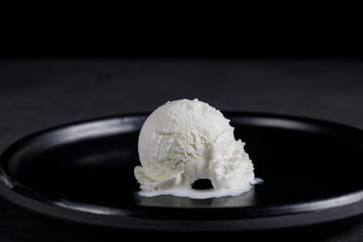 White cream ball on a black ceramic dish on a dark background