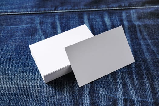 Mockup of blank business cards on denim background.