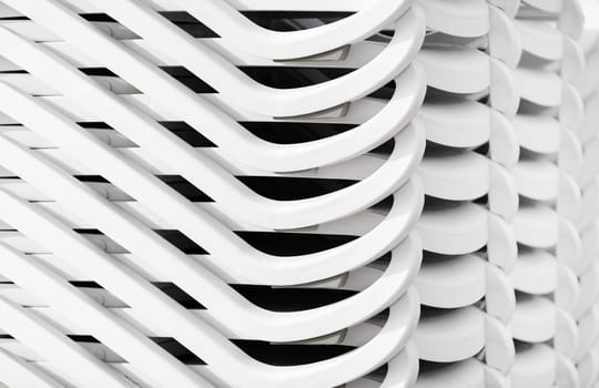 Stacked white plastic beach loungers. Abstract background.