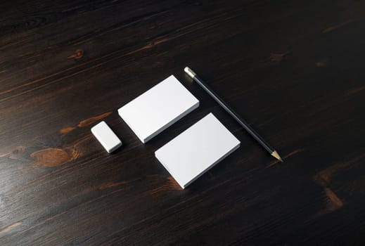 Blank business cards, pencil and eraser on wooden background. Stationery template for placing your design.