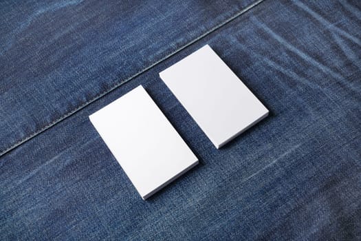 Stacks of white blank business cards on denim background. Template for graphic designers portfolios.