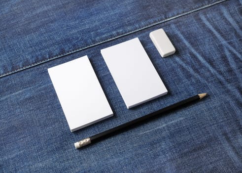 Photo of blank business cards, pencil and eraser on denim background. Stationery mock up. Template for placing your design.
