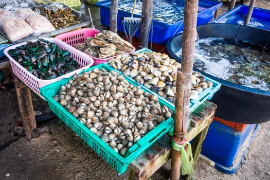 Thai bazaar with variety of fresh clams, mussels, shellfish, prawns and langoustes in baskets and tanks, Phuket, Thailand