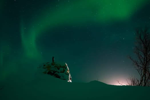 Awesome display of aurora borealis northern lights above the stone marker on the border between Finland and Norway