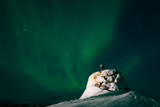 Awesome display of aurora borealis northern lights above the stone marker on the border between Finland and Norway