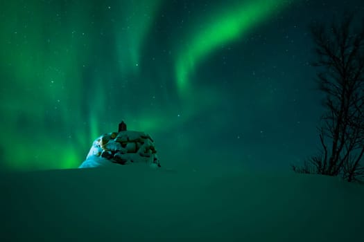 Awesome display of aurora borealis northern lights above the stone marker on the border between Finland and Norway