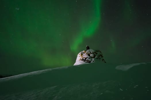 Awesome display of aurora borealis northern lights above the stone marker on the border between Finland and Norway